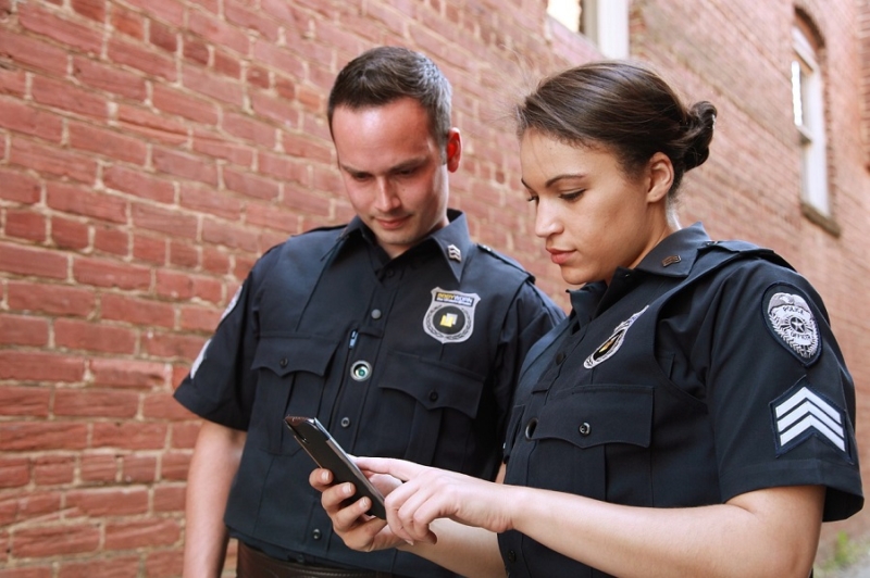 coppia di poliziotti con smartphone in mano